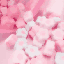 a pile of pink and white flower shaped marshmallows on a pink surface