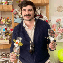 a man in a blue jacket is holding a chocolate lollipop with flowers on it