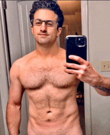 a shirtless man taking a selfie with a cell phone