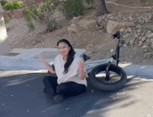 a woman sits on the ground next to a bike