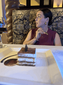 a woman sits at a table with a piece of cake on a plate