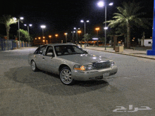 a silver mercury car is parked on a brick street at night