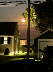 a full moon is visible over a house and garage