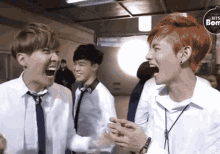 a man with red hair is laughing with another man in a white shirt