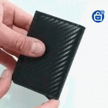 a person is holding a black wallet in their hand with their finger .