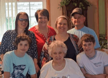 a group of people are posing for a picture with an older woman in a wheelchair .