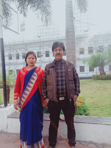 a man and a woman are posing for a picture in front of a building that is under construction