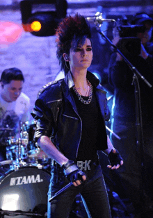 a man is standing in front of a tama drum set