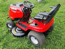 a red oregon bill lawn mower is parked in a grassy field