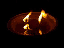 two candles are burning in a bowl of liquid in the dark .