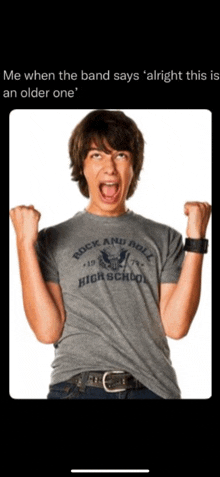 a young man wearing a rock and roll high school t-shirt with his fist in the air .