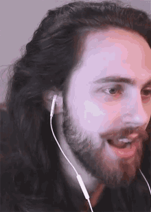 a man with long hair and a beard is wearing earbuds