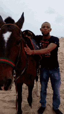 a man standing next to a horse on the beach