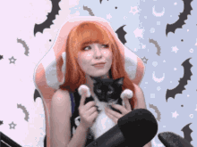 a woman in a pink chair holds a black and white cat in her arms