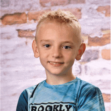 a young boy wearing a brooklyn shirt smiles for the camera