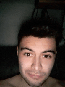 a close up of a man 's face with a beard looking at the camera in a dark room .