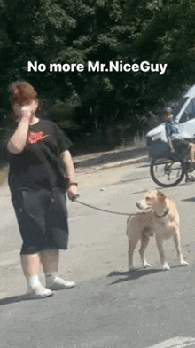 a man is walking a dog on a leash down a street .