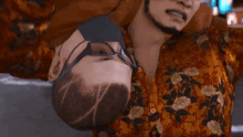 a man in a floral shirt holds another man 's head upside down