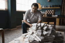 a man sits in a chair surrounded by stacks of dollar bills