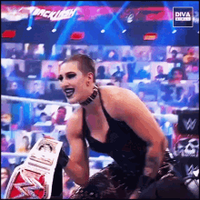 a woman in a black dress is holding a diva belt in front of a crowd