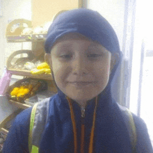 a young boy wearing a blue jacket with a hood is smiling for the camera