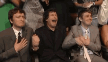 three men in suits and ties are clapping and laughing together