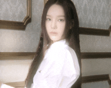 a woman with long hair is wearing a white shirt and looking at the camera