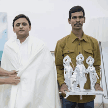 a man in a yellow shirt holds a statue of a woman