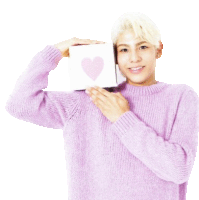 a man in a purple sweater holds a card with a pink heart on it