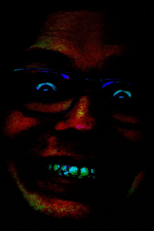 a close up of a person 's face with glasses in the dark