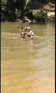 two people in the water taking a selfie with their cell phones