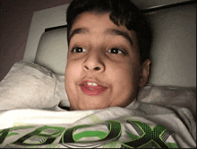 a boy wearing a shirt that says xbox laying on a bed