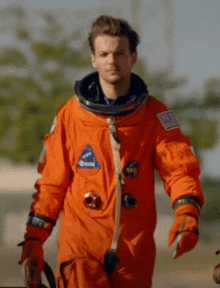 a man in an orange space suit with nasa patches on it