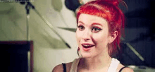 a woman with red hair is smiling and looking at the camera in a room .