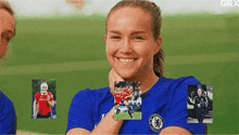 a woman in a blue soccer jersey is smiling and holding a picture of herself .