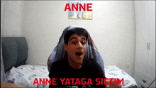 a young man is sitting in front of a bed with the words anne yataga sictim written in red