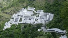 a group of white buildings sitting on top of a hill surrounded by trees .