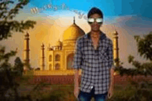 a young man wearing sunglasses is standing in front of a mosque .