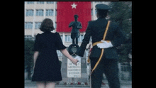 a woman in a black dress holds the hand of a soldier