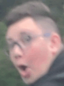 a blurry picture of a man wearing glasses with his mouth open .