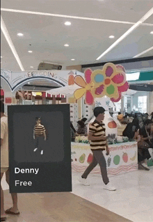 a man in a striped shirt is walking in front of a sign that says denny free