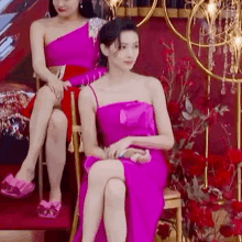 a woman in a pink dress is sitting next to another woman in a red chair .