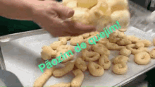 a person is pouring dough into a tray of cookies with the words paozin de quejim written on it .