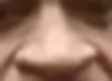 a blurry picture of a woman 's nose with a blurred background .