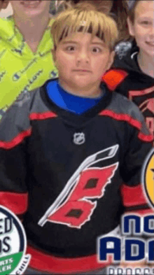 a young boy wearing a carolina hurricanes jersey poses for a picture