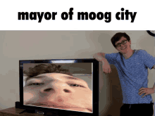 a man leaning against a television with the words mayor of moog city written above him