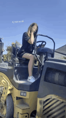 a woman is sitting on a yellow and black heavy machinery that says cesty