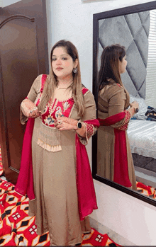 a woman is standing in front of a mirror wearing a brown and pink dress