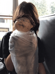 a person holding a doll wrapped in plastic