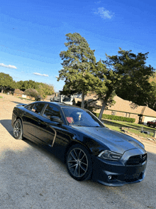 a black car is parked in a gravel lot